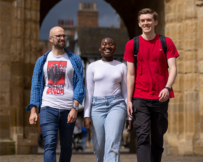 Three students walking with an archway behind them