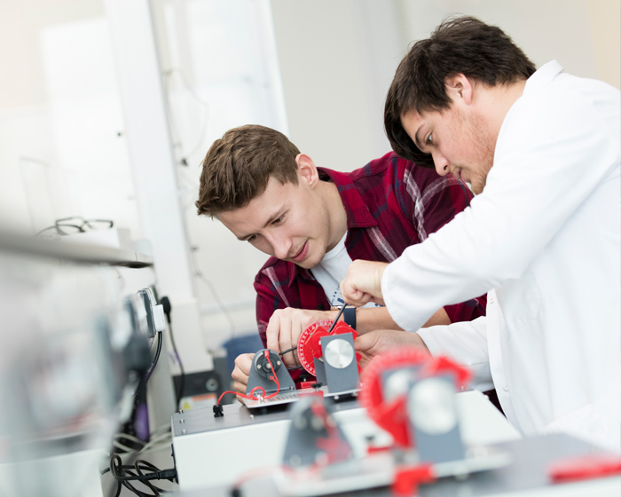 Two engineering students working on a mechanism in a lab