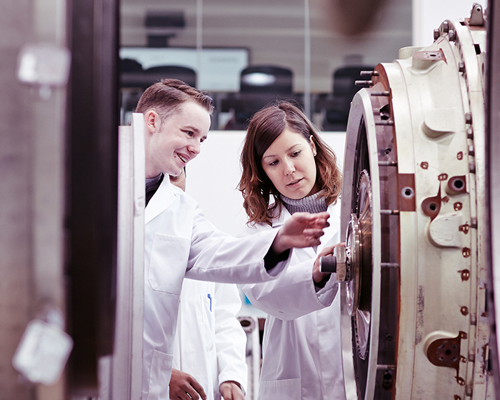 Student and a staff member in white coats, examining a turbine engine